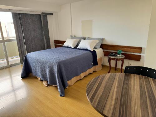 Flat Particular Hotel Saint Paul في برازيليا: غرفة نوم بسرير وطاولة