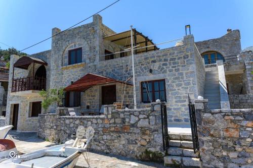 a stone house with a boat in front of it at Sikies Stone House On The Beach in Khalíkia