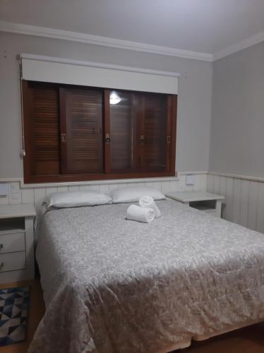 a bedroom with a bed with two towels on it at Solar das Esmeraldas - Apto 105 in Gramado