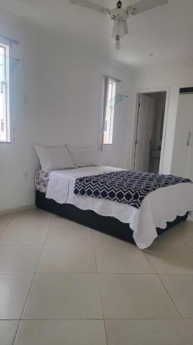un letto in una camera bianca con due finestre di Pousada Pé na Areia Rio das Ostras a Rio das Ostras