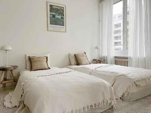 2 camas blancas en una habitación blanca con ventana en Charmantes Apartment inmitten Zürich-Affoltern & Netflix!, en Zúrich