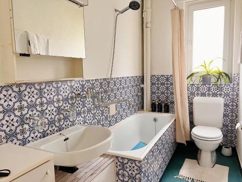 La salle de bains est pourvue d'une baignoire blanche et de toilettes. dans l'établissement Charmantes Apartment inmitten Zürich-Affoltern & Netflix!, à Zurich