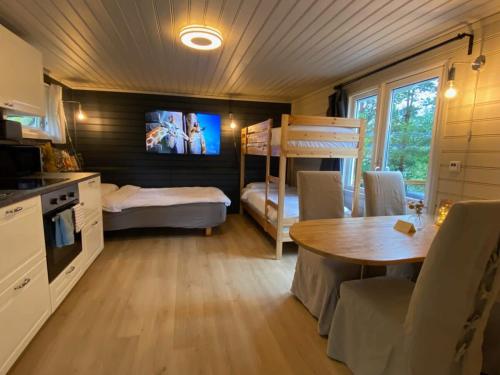 a kitchen and dining room with a table and bunk beds at Kveldsro cabin in nice surroundings in Kristiansand