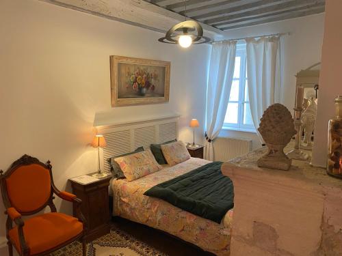 1 dormitorio con 1 cama y 1 silla en Le pigeonnier de Saint-Loup Bed and Breakfast, en Saint-Loup-de-Varenne
