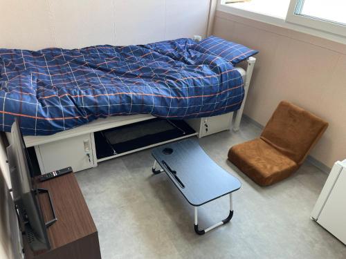 a small bedroom with a bed and a chair at ５８ビレッジ種子島 in Ishidera