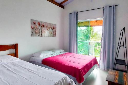 um quarto com 2 camas e uma janela em Chalés João&Maria - Ilhabela em Ilhabela