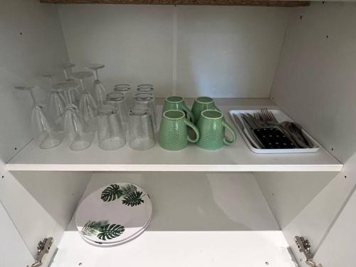 estantería con tazas verdes y otros utensilios de cocina en Bungalow Natura - Sarramea en Sarraméa