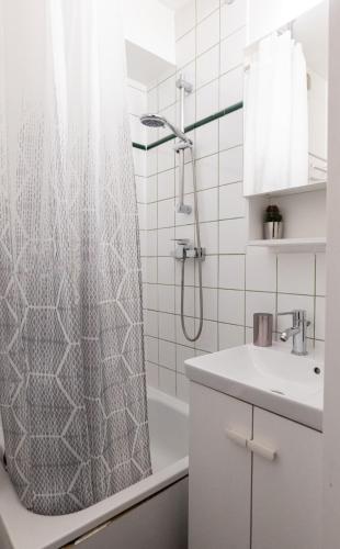 une salle de bain avec un rideau de douche et un lavabo dans l'établissement Cosy Appartement - 4 personnes - Disneyland & Paris, à Bussy-Saint-Georges