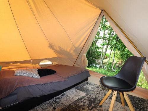 een slaapkamer met een bed en een stoel in een tent bij Beautiful safari tent in Twijzel with terrace in Twijzel