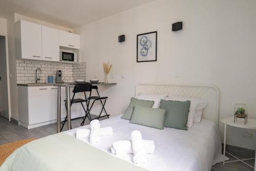 - une chambre blanche avec un lit blanc et une cuisine dans l'établissement Fabulous Appartement - Disneyland & Paris, à Bussy-Saint-Georges