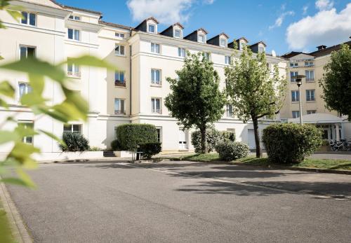 un grand bâtiment blanc avec des arbres devant lui dans l'établissement Fabulous Appartement - Disneyland & Paris, à Bussy-Saint-Georges