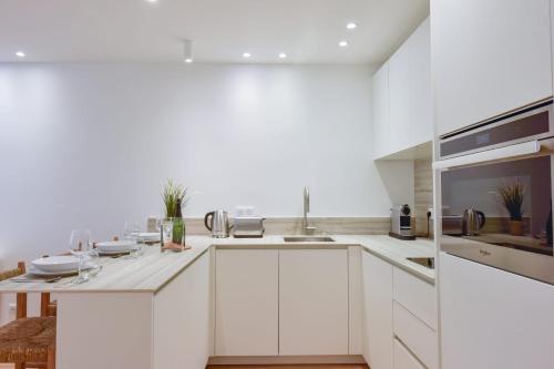 une cuisine blanche avec des armoires blanches et un évier dans l'établissement Upscale 1-Br apartment 100 meter from the Palais des Festivals, à Cannes