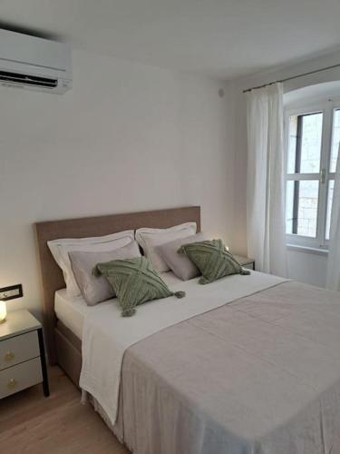 a white bedroom with a large bed with pillows at House Mvsevm 4* in Vis