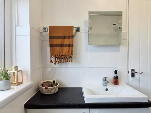 ein Bad mit einem Waschbecken und einem Spiegel in der Unterkunft Contemporary 3 bedroom house in Nottingham