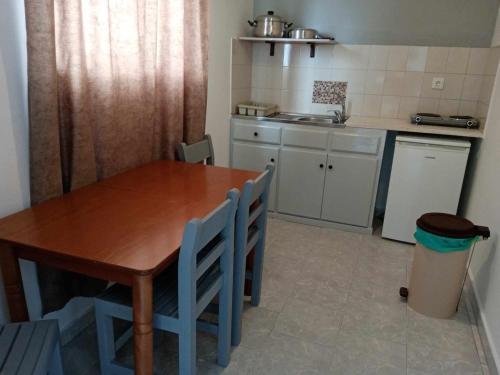 cocina con mesa de madera y sillas azules en Dennis Apartments en Kalamaki