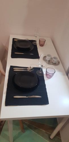 a white table with black plates and glasses on it at CasaAlma in Serdiana