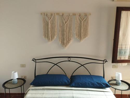 a bedroom with a bed with blue pillows and two tables at Poppy's House in Torre Dei Corsari