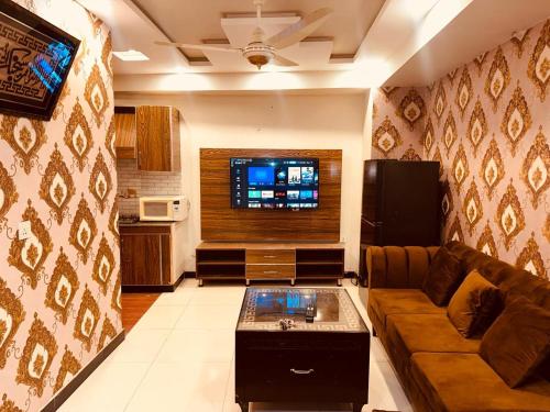 Il comprend un salon doté d'un canapé et d'une télévision à écran plat. dans l'établissement Sweet Homes Apartments, à Lahore