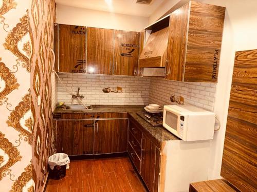 - une petite cuisine avec des placards en bois et un four micro-ondes dans l'établissement Sweet Homes Apartments, à Lahore