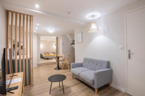 a living room with a couch and a table at Le Triplex - 8 pers - Hypercentre - Wifi in LʼIsle-sur-la-Sorgue