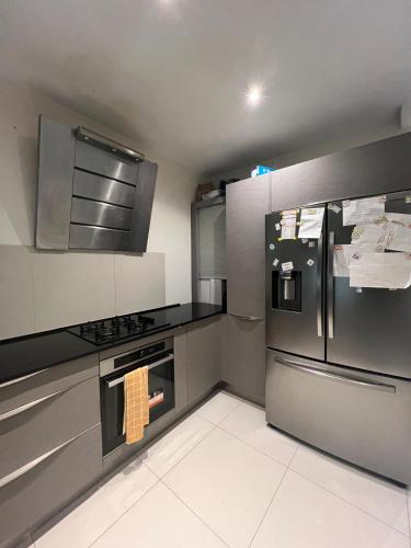 Il comprend une cuisine équipée d'un réfrigérateur et d'une cuisinière en acier inoxydable. dans l'établissement ma maison, la votre, à Les Pavillons-sous-Bois