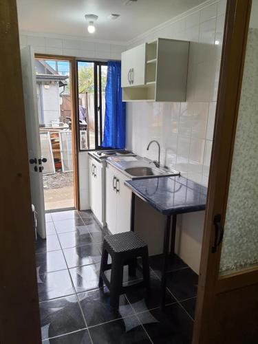 eine Küche mit einer Theke, einer Spüle und einem Stuhl in der Unterkunft Departamento Interior Pablo Neruda in Temuco