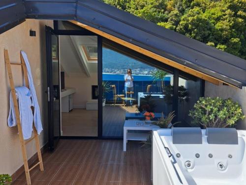 a balcony with a tub and a woman standing outside at Rea Boutique Hotel in Himare
