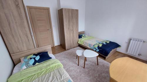 a bedroom with two beds and a table and a chair at HOPE Apartment in Vodno