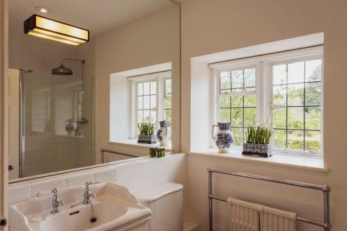 uma casa de banho com um lavatório, um espelho e janelas em 7 Bedrooms Manor Farmhouse with heated pool em Cirencester