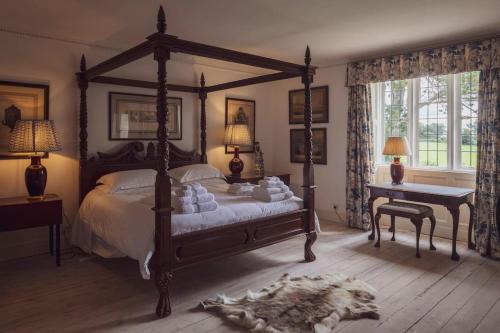 um quarto com uma cama de dossel e uma secretária em 7 Bedrooms Manor Farmhouse with heated pool em Cirencester