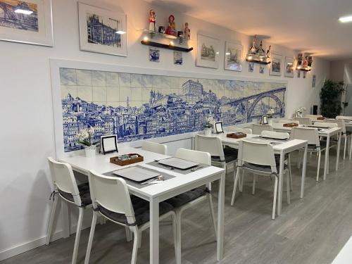 un comedor con mesas blancas y sillas blancas en Guest House Triunfo, en Oporto
