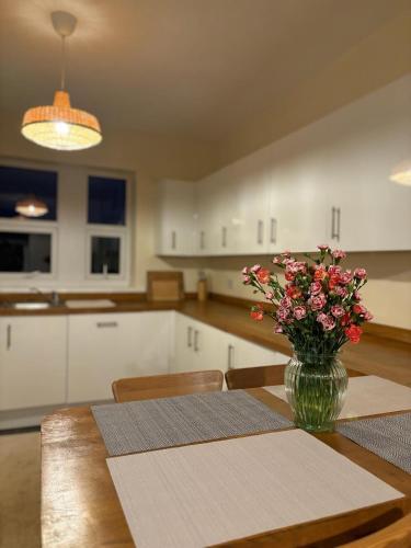 a dining room table with a vase of flowers on it at Cardiff/Pernath Home2 in Cardiff