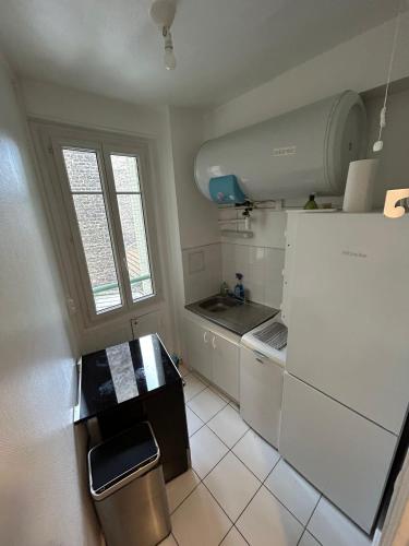 małą kuchnię z białymi szafkami i lodówką w obiekcie Nice apartement near to Paris w mieście Neuilly-sur-Seine