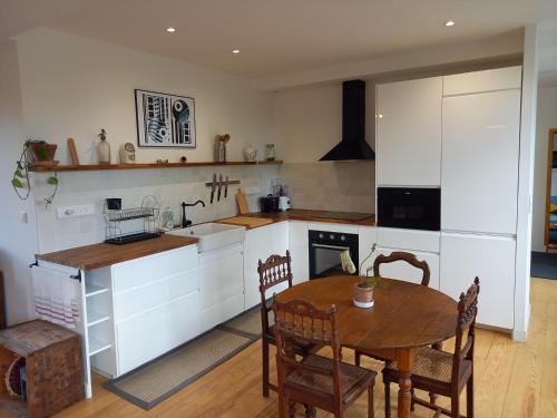 une cuisine avec une table en bois et une table et des chaises dans l'établissement Le Gîte du Moulin, à Saint-Félix