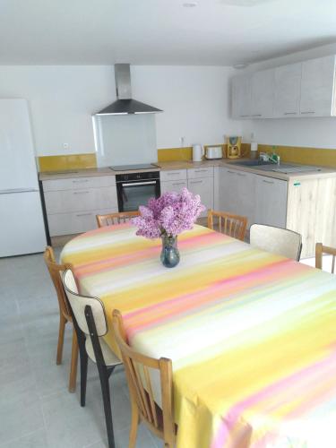 une cuisine avec une table avec un vase de fleurs dessus dans l'établissement Le Tilleul 9 personnes 5 Chambres 6 lits 15 min du Futuroscope, à Yversay