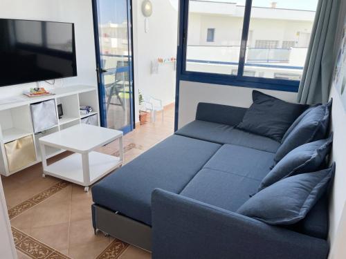 a living room with a blue couch and a tv at Apartamento Vilem & Piscina, Wi-Fi in Costa Calma