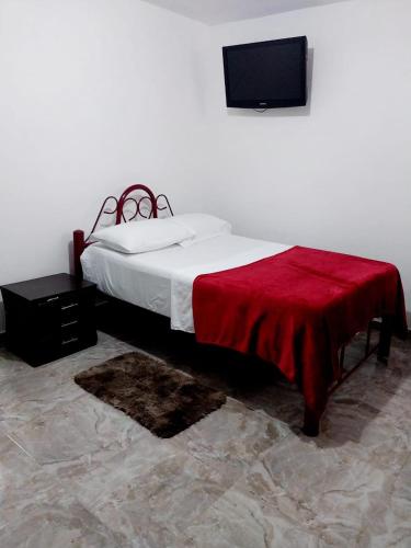 Un dormitorio con una cama con una manta roja. en Habitación Cómoda en Familia, en Ibagué