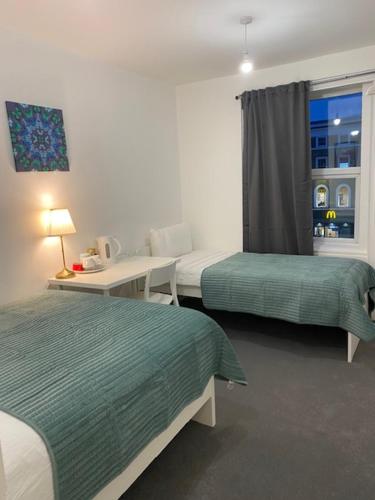 a hotel room with two beds and a window at Lord Merit Guest Rooms in King's Cross St Pancras in London