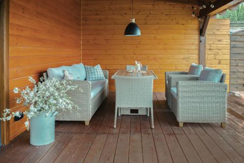 a patio with wicker chairs and a table with a vase of flowers at Dom Całoroczny Pola w Sierakowie in Sieraków