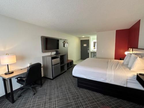 a hotel room with a bed and a desk and a television at Ramada by Wyndham Waupaca in Waupaca