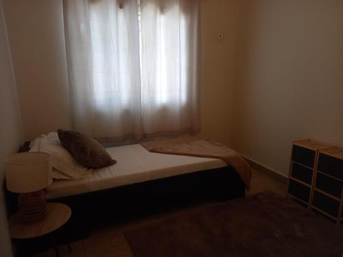 a small bedroom with a bed with a window at Modern Bungalow with private pool and patio in Old Yundum