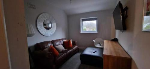 a living room with a brown leather couch and a mirror at James House in Bescot