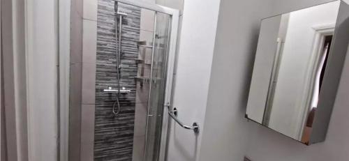a bathroom with a glass shower and a mirror at James House in Bescot