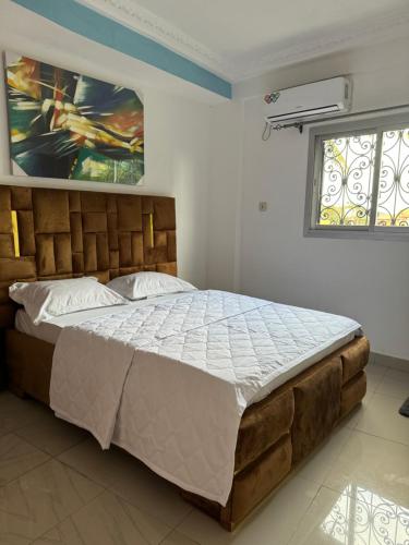 a bedroom with a large bed with a painting on the wall at Lekker Estate in Yaoundé