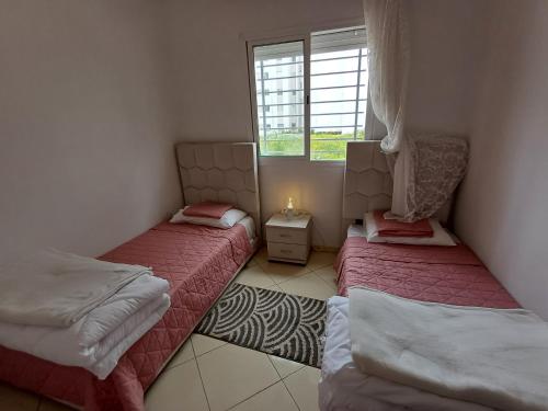 2 camas en una habitación pequeña con ventana en Super et nouvel appart proche de la plage, en Temara