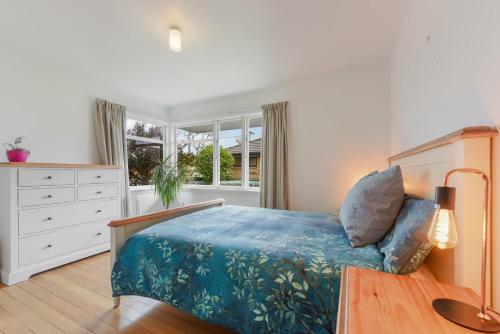 a bedroom with a bed and a dresser and a window at Lush Oasis - Blenheim Holiday Home in Blenheim