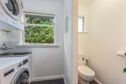 a bathroom with a washing machine and a window at Lush Oasis - Blenheim Holiday Home in Blenheim