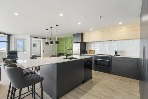 a kitchen with a large island with bar stools at Oceanstyle on Main in Mount Maunganui