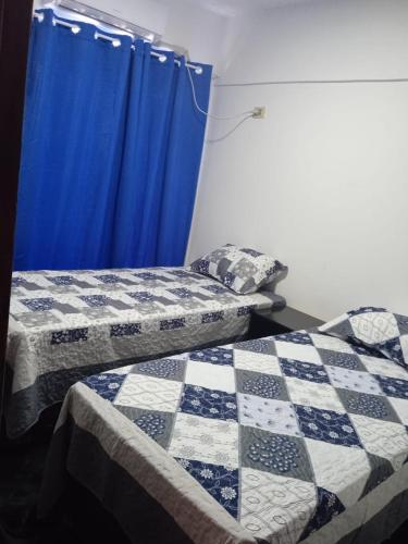 - 2 lits dans une chambre avec un rideau bleu dans l'établissement EDIFICIO PROGRESO, à Ciudad del Este