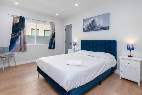 een slaapkamer met een groot bed met een blauw hoofdeinde bij Prime Location, Stylish Space: 3BR Home with BBQ in Los Angeles